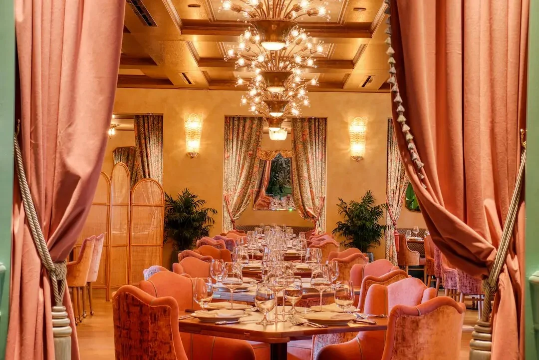 Salle à manger principale de Casadonna encadrée de rideaux roses et de lustres